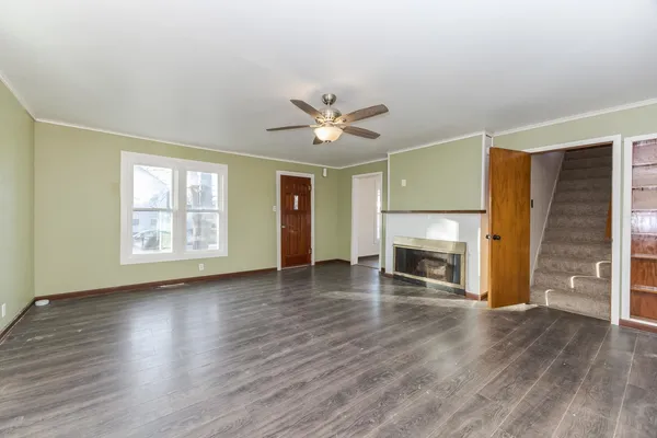 an empty room with windows a fireplace and wooden floor