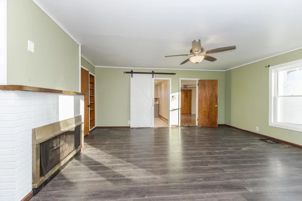 a view of an empty room with window and wooden floor