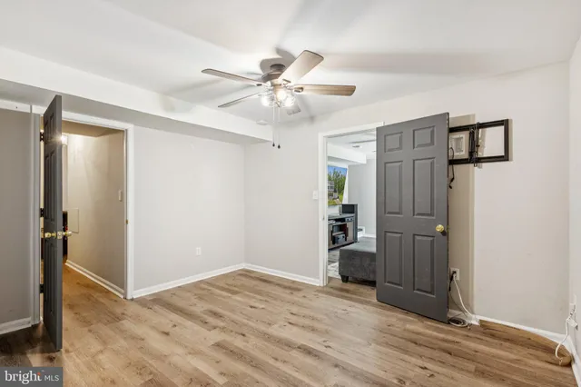 a view of empty room with wooden floor and ceiling fan