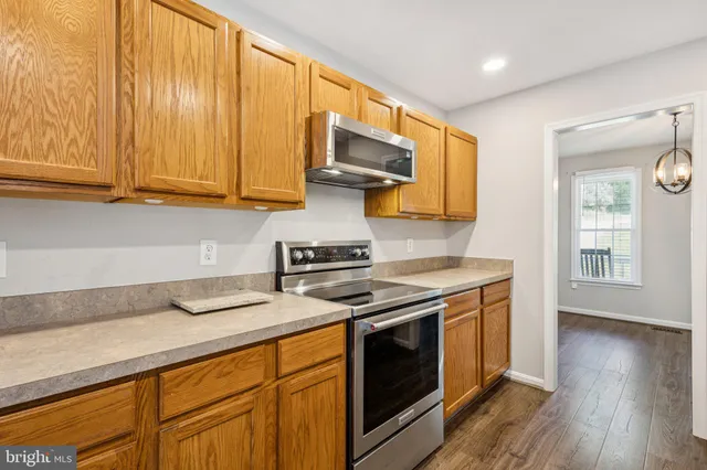 a kitchen with stainless steel appliances granite countertop a sink a stove and a wooden floors