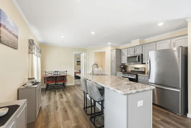 a kitchen with a refrigerator a stove and white cabinets with wooden floor
