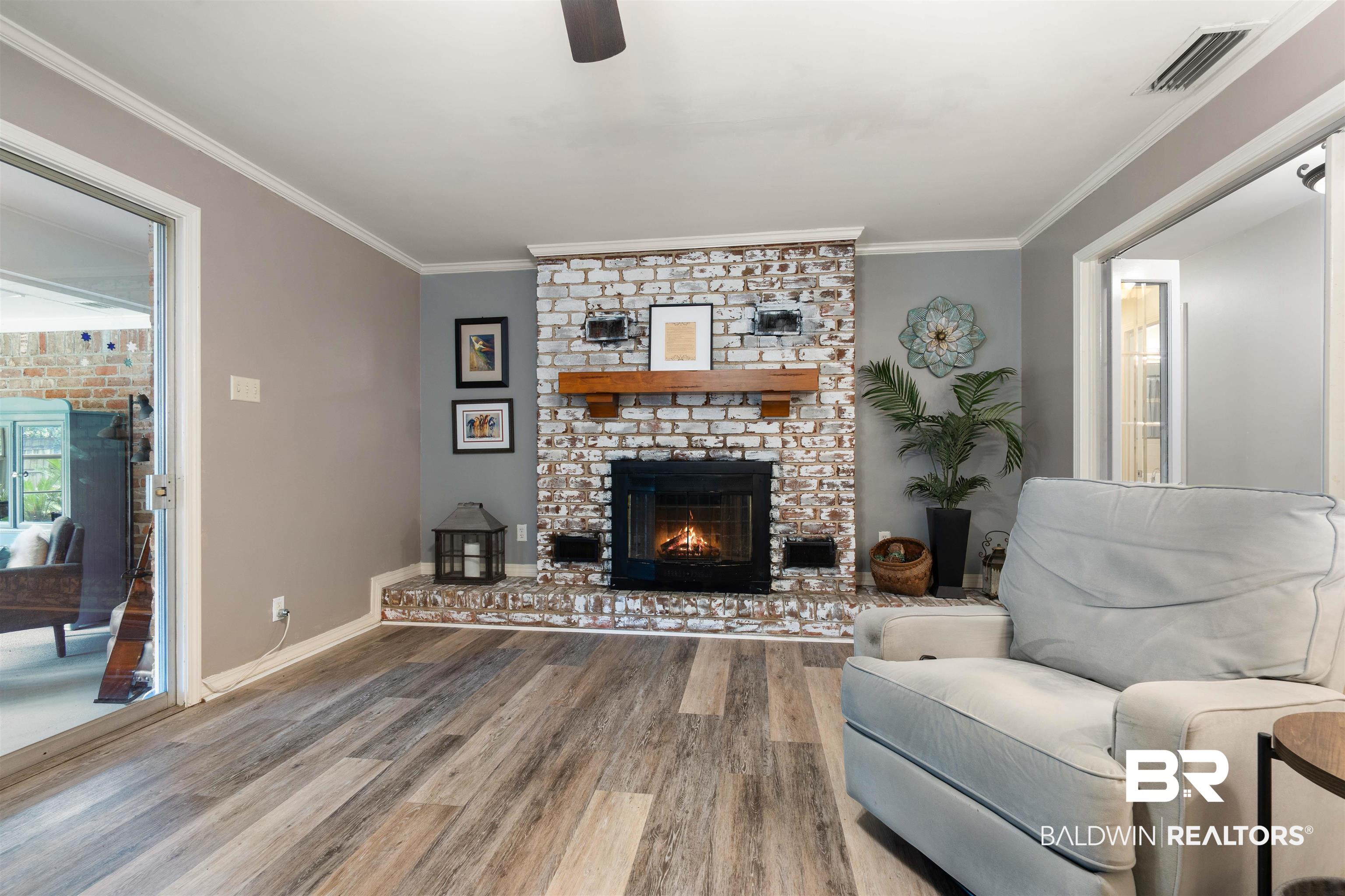 4051 East Canal Circle Mobile, AL 36619 - Photo 6 of 32 Living room with ornamental molding, a brick fireplace, hardwood / wood-style flooring, and ceiling fan
