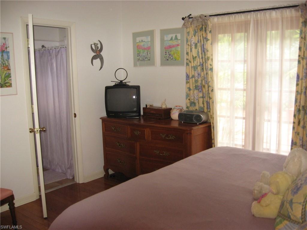 5150 Sand Dollar Lane Naples, FL 34103 - Photo 8 of 16 a bedroom with a bed and a flat tv screen