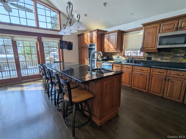 a kitchen with stainless steel appliances granite countertop a stove a sink dishwasher a dining table and chairs with wooden floor