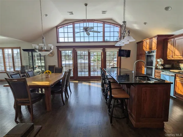 a dining room with wooden floor a chandelier a wooden table and chairs