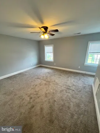 an empty room with a chandelier fan and windows