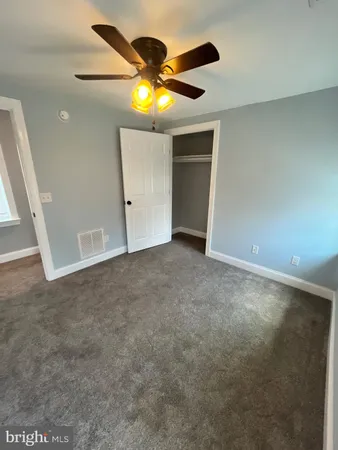 an empty room with closet and a chandelier fan