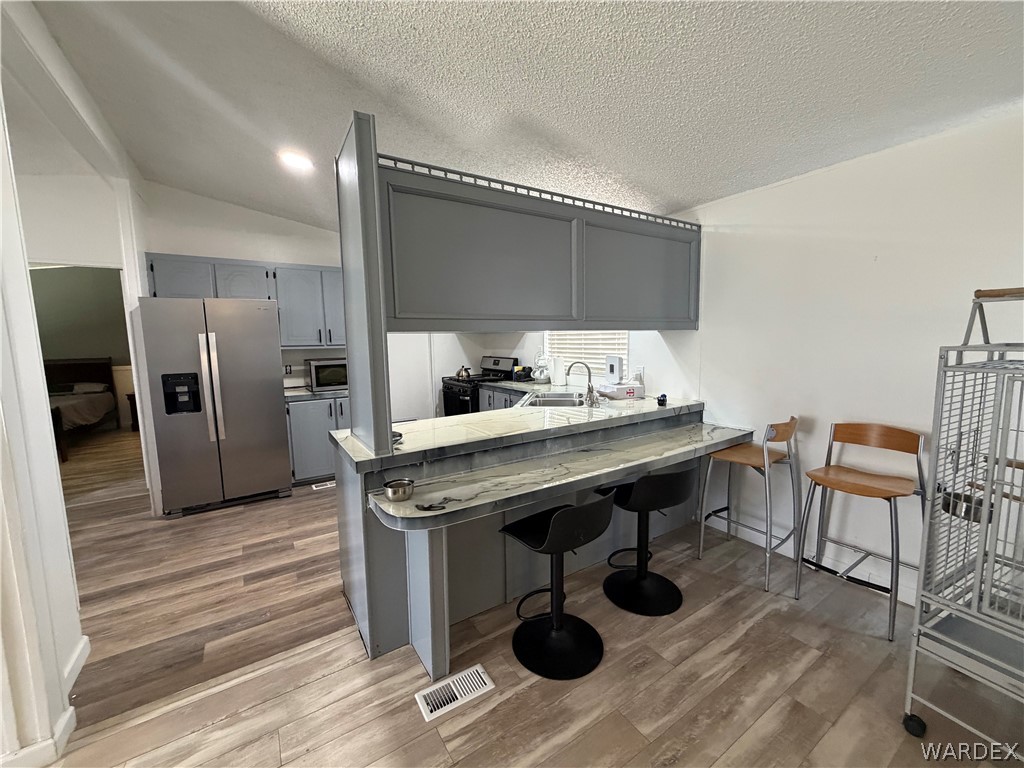 1910 Rio Grande Road Bullhead City, AZ 86442 - Photo 10 of 29 Kitchen featuring gray cabinetry, stainless steel refrigerator, and wood-finish flooring