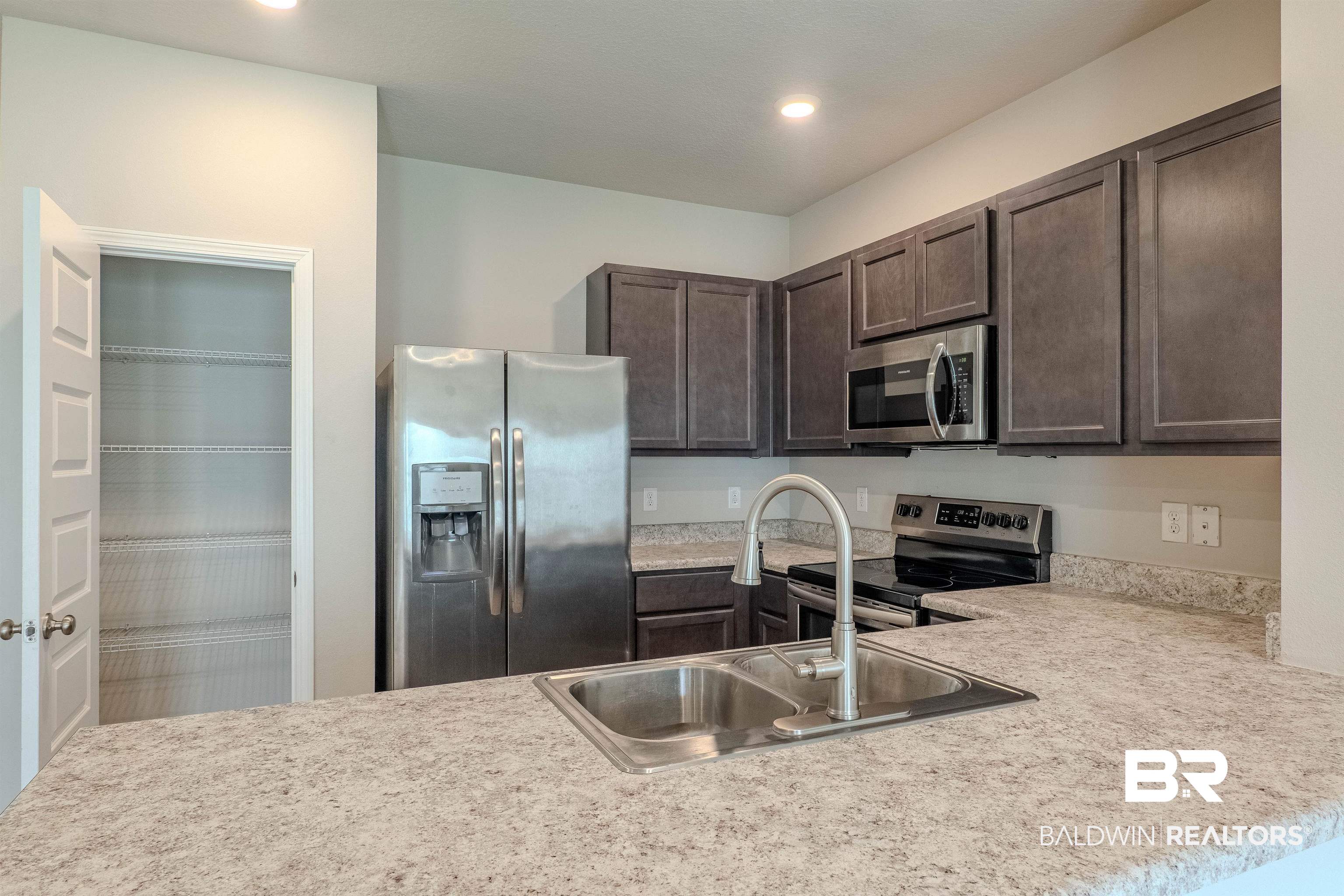 25806 Pollard Road, Unit 32 Daphne, AL 36526 - Photo 5 of 23 Kitchen with kitchen peninsula, appliances with stainless steel finishes, dark brown cabinetry, and sink