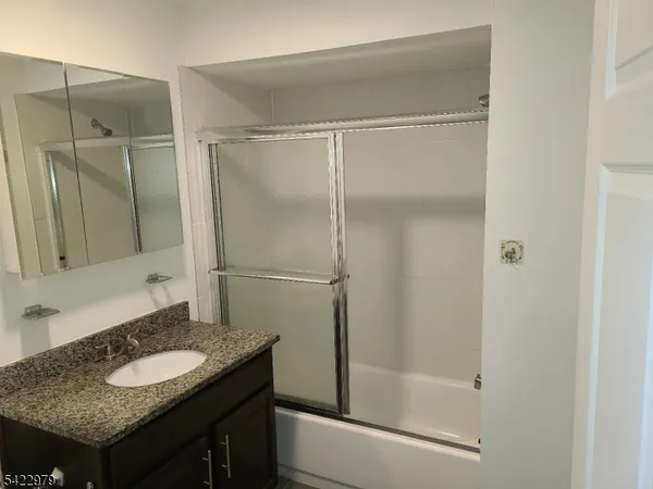 a bathroom with a granite countertop sink shower and a mirror