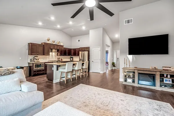 a living room with stainless steel appliances furniture and a flat screen tv