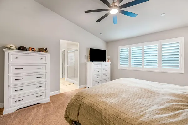 a bedroom with a bed a flat tv screen and a chandelier