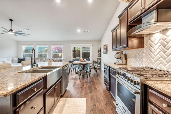 a kitchen with stainless steel appliances granite countertop a stove top oven a sink dishwasher and cabinets with wooden floor