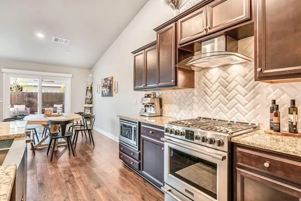 a kitchen with stainless steel appliances granite countertop a stove and a wooden floors
