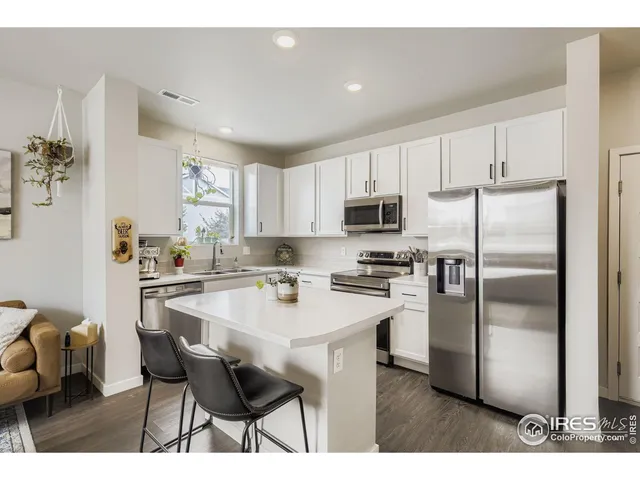 a kitchen with kitchen island a refrigerator and a stove top oven