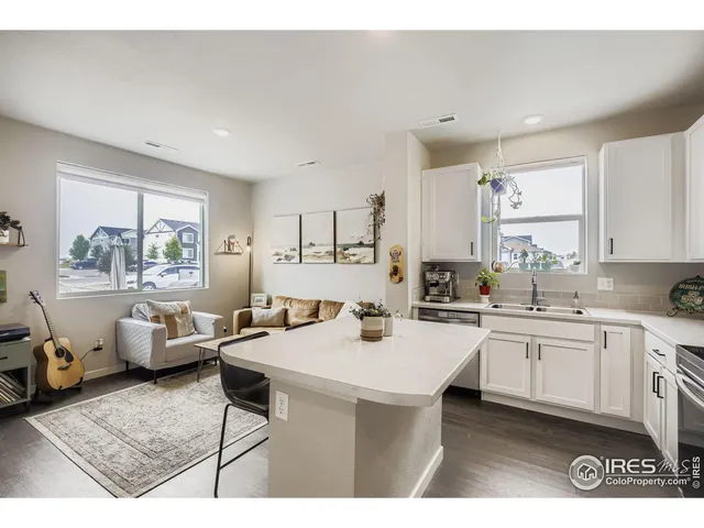 a open kitchen with stainless steel appliances kitchen island granite countertop a sink dishwasher and white cabinets with wooden floor