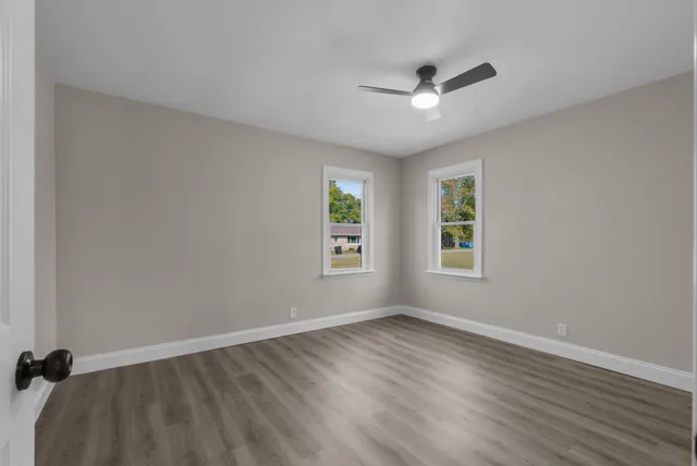 an empty room with wooden floor and ceiling fan