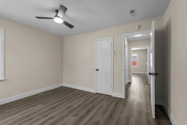 an empty room with wooden floor cabinet and windows