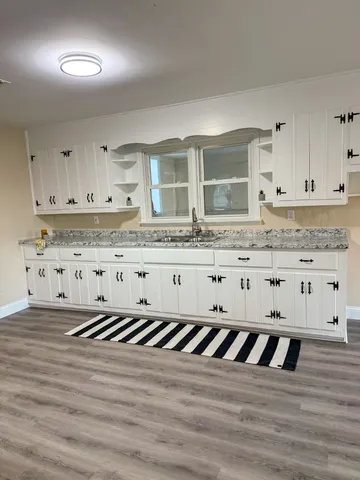 a large kitchen with granite countertop a large window a sink and stainless steel appliances