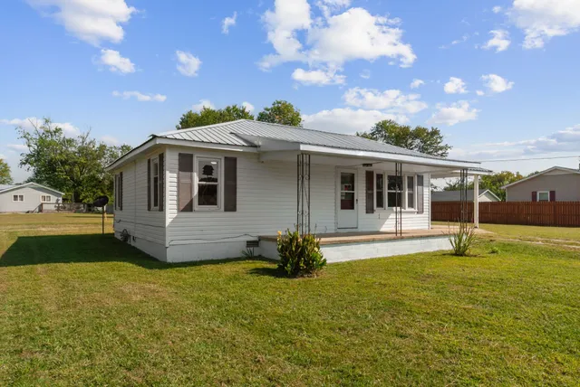a view of a house with a big yard and large tree