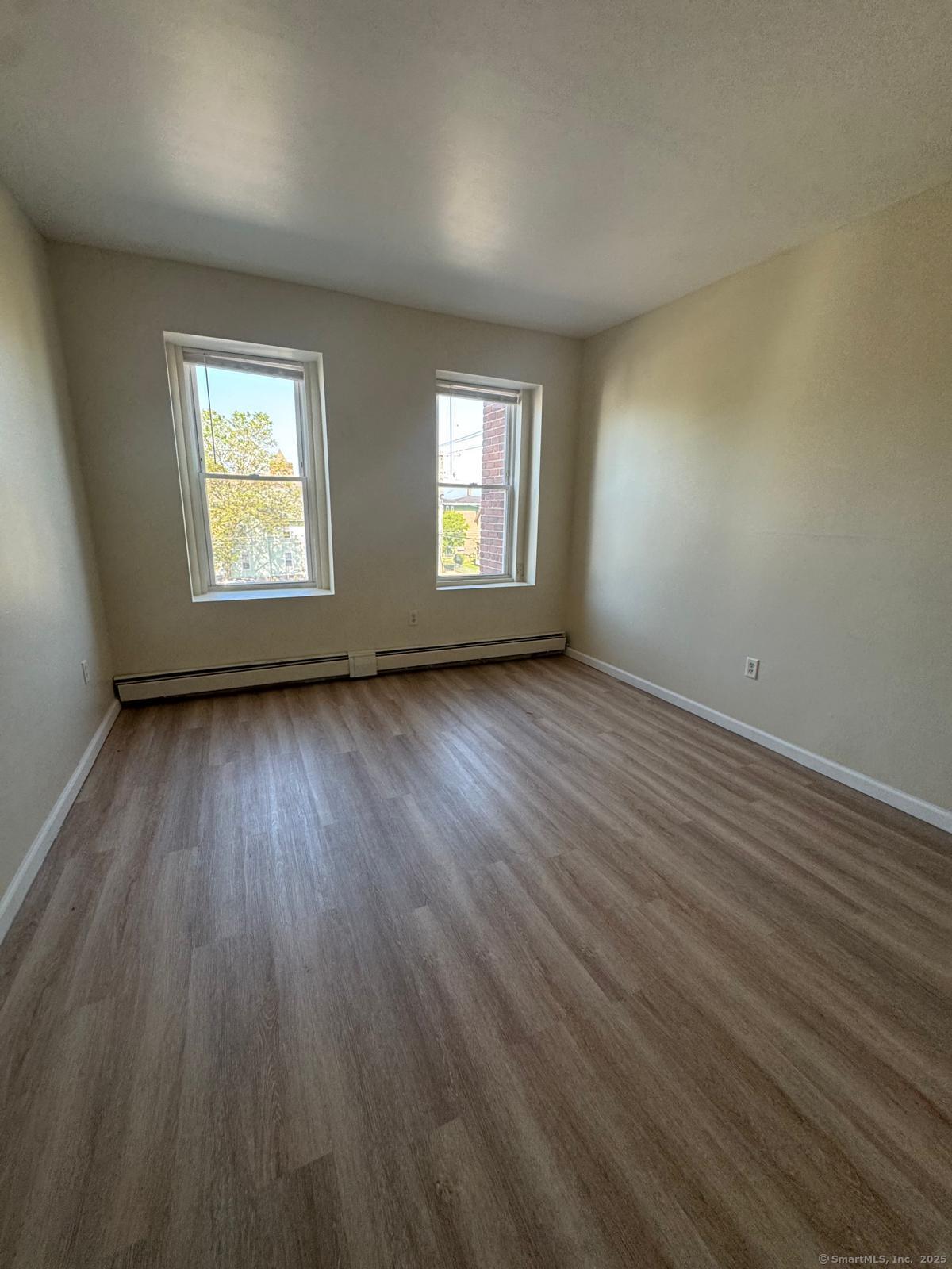 1053 East Main Street, Unit 8 Bridgeport, CT 06608 - Photo 2 of 4 an empty room with wooden floor and windows