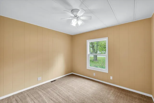 an empty room with a window and a ceiling fan