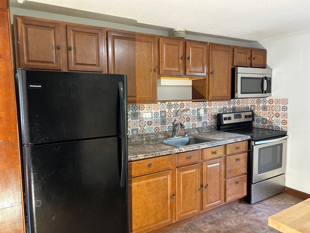 67 Everard Street Worcester, MA 01605 - Photo 4 of 13 a kitchen with granite countertop stainless steel appliances and refrigerator