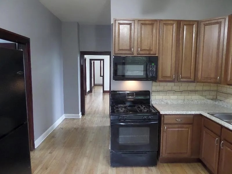 2836 East 84th Street Chicago, IL 60617 - Photo 3 of 7 a kitchen with granite countertop a stove and a wooden cabinets