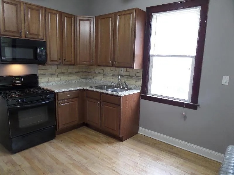 2836 East 84th Street Chicago, IL 60617 - Photo 4 of 7 a kitchen with granite countertop wooden cabinets and a stove top oven