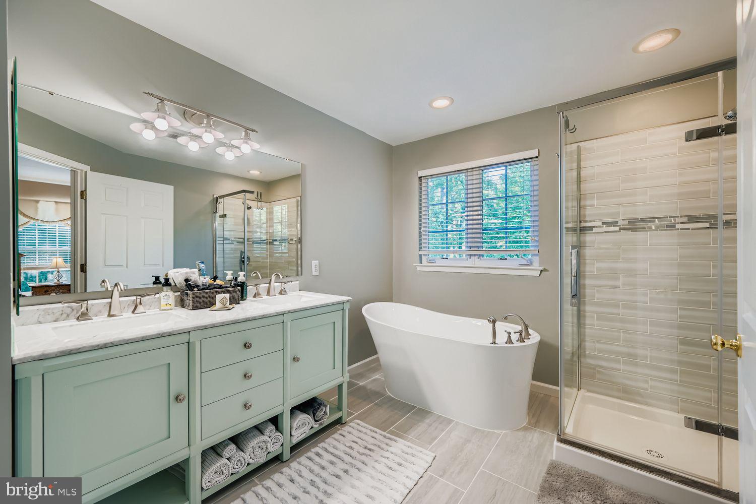 9809 Redwing Drive, Unit 9809 Perry Hall, MD 21128 - Photo 16 of 42 a bathroom with a white tub a vanity a sink and mirror
