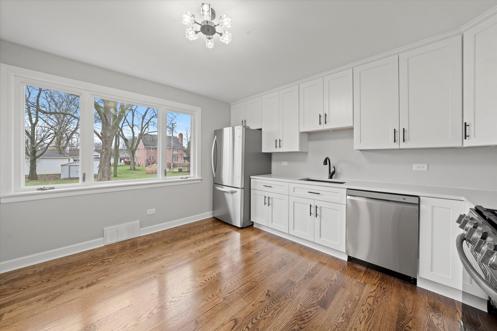 5426 Wolf Road Western Springs, IL 60558 - Photo 6 of 19 a kitchen with granite countertop white cabinets a refrigerator a sink a stove and wooden floors