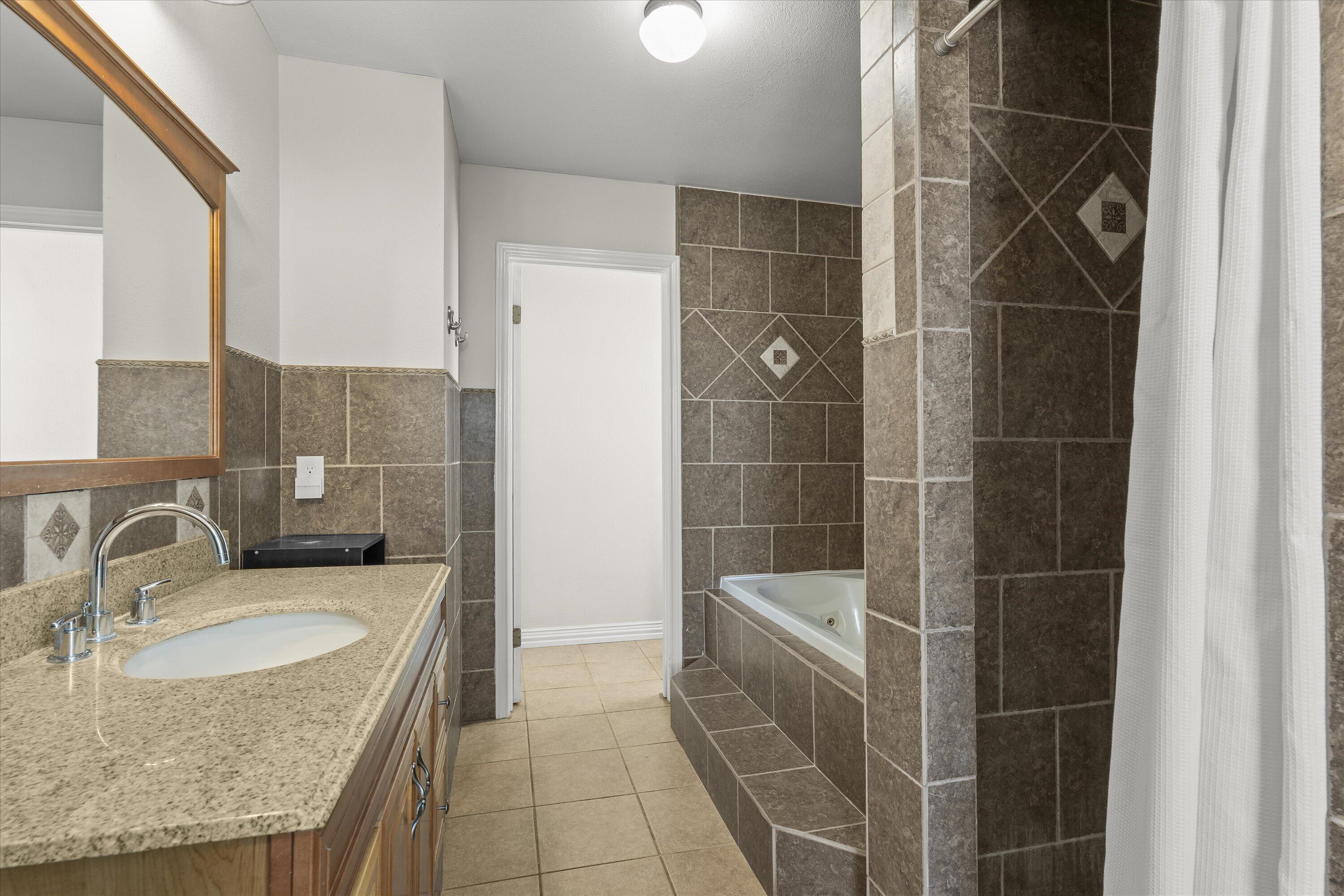 3131 North Alamo Road Levelland, TX 79336 - Photo 13 of 32 a bathroom with a granite countertop sink a shower and a mirror