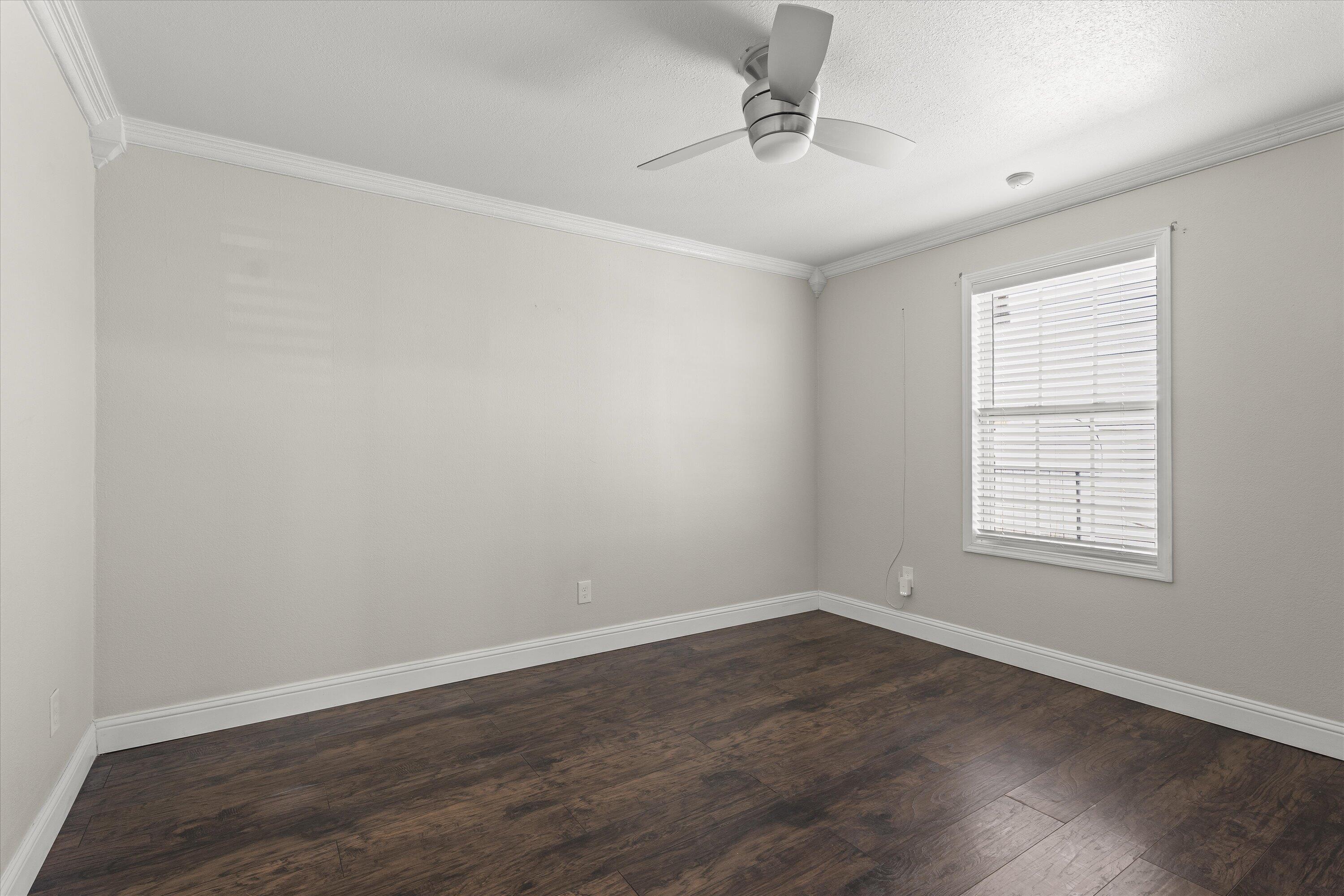 3131 North Alamo Road Levelland, TX 79336 - Photo 18 of 32 an empty room with wooden floor and windows
