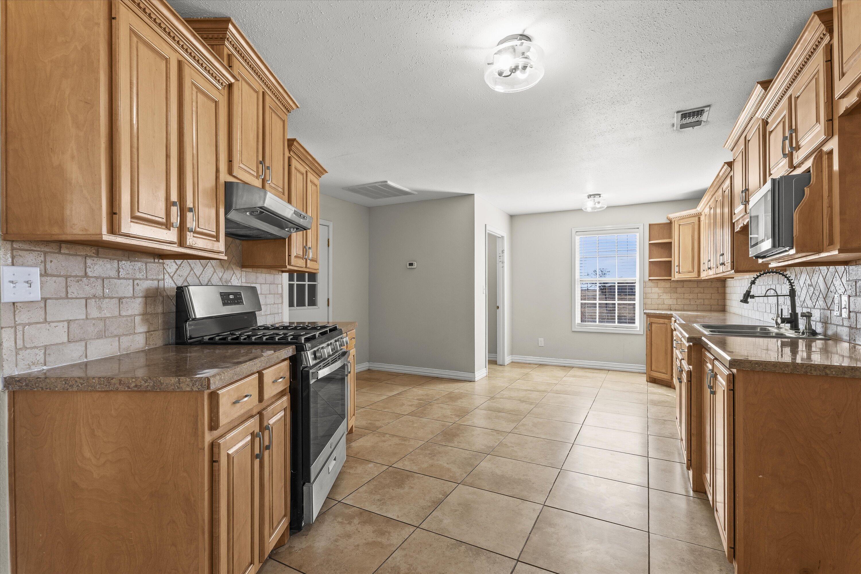 3131 North Alamo Road Levelland, TX 79336 - Photo 8 of 32 a kitchen with stainless steel appliances granite countertop a stove a sink and a refrigerator