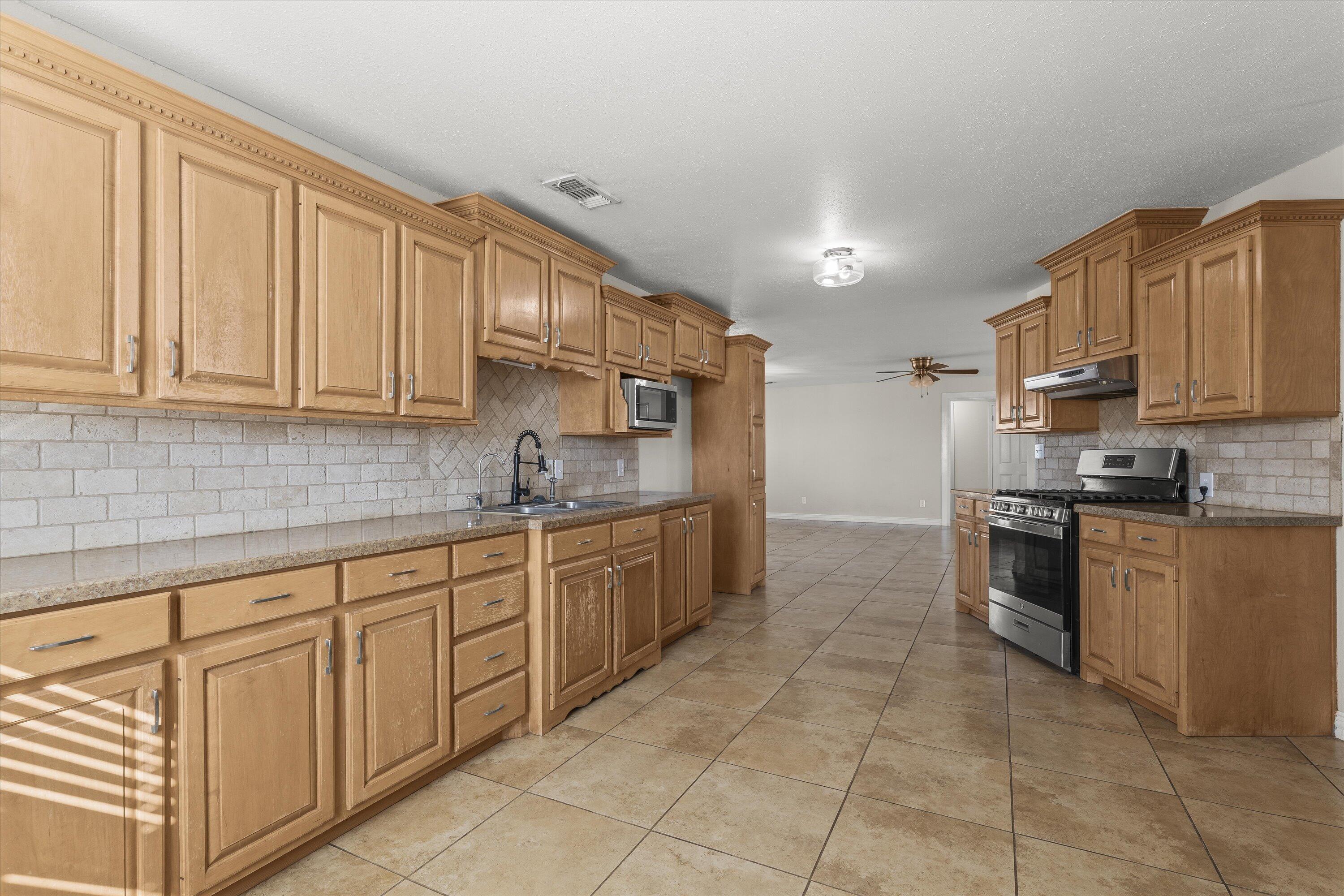 3131 North Alamo Road Levelland, TX 79336 - Photo 9 of 32 a kitchen with stainless steel appliances granite countertop a sink and cabinets