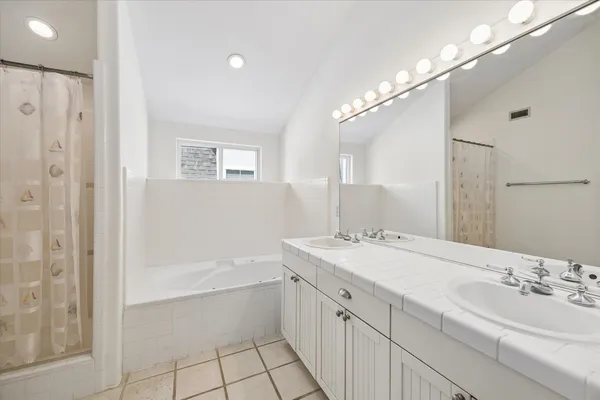 a bathroom with a bathtub a double vanity sink and mirror