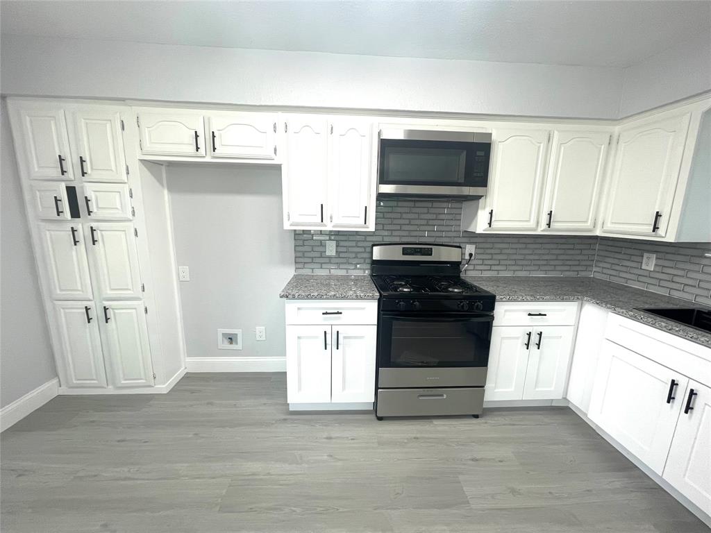 5146 Fm 879 Palmer, TX 75152 - Photo 1 of 1 a kitchen with granite countertop a refrigerator stove and white cabinets