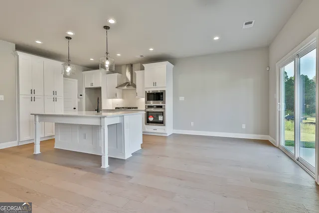 a large kitchen with a large counter top a sink stainless steel appliances and cabinets