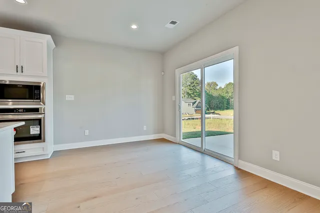 a view of an empty room with a window and wooden floor