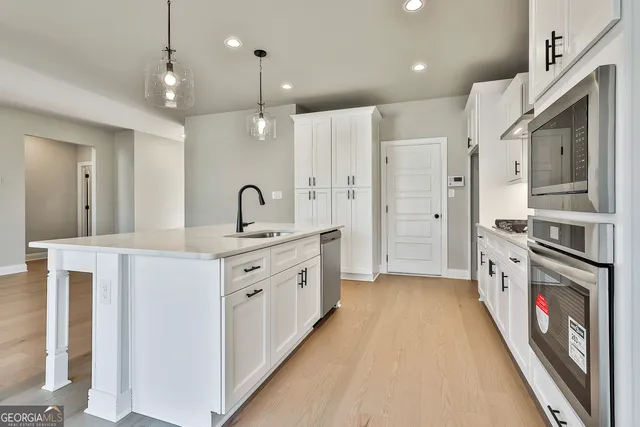a large kitchen with a large counter top a sink stainless steel appliances and cabinets