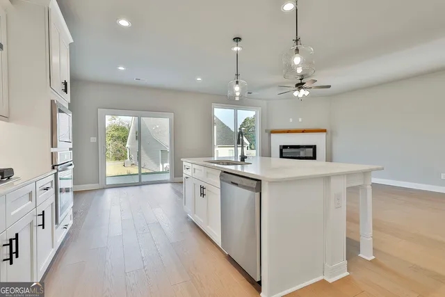 a kitchen with stainless steel appliances granite countertop a sink a stove a refrigerator and a window