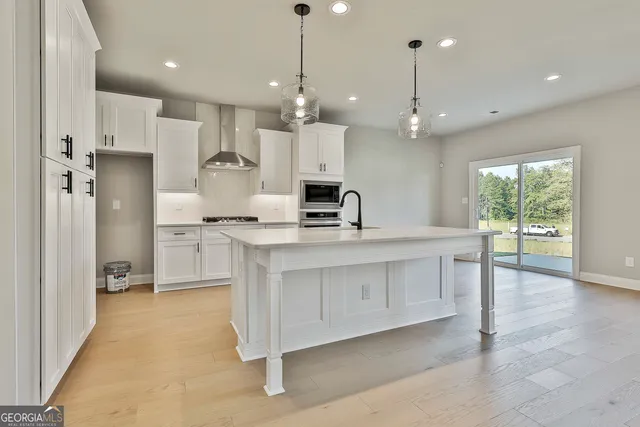 a large kitchen with white cabinets stainless steel appliances a sink and a large window