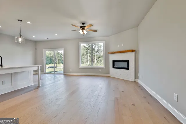 an empty room with wooden floor fireplace and windows