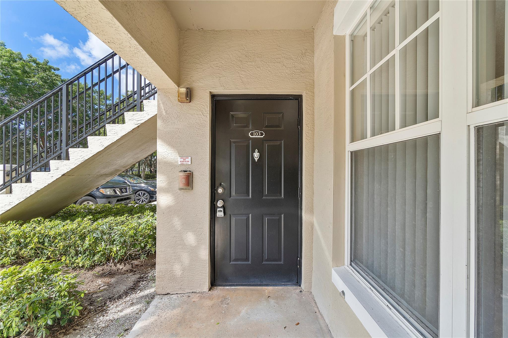 6020 West Sample Road, Unit 103 Coral Springs, FL 33067 - Photo 3 of 20 a view of a wooden door with a small yard