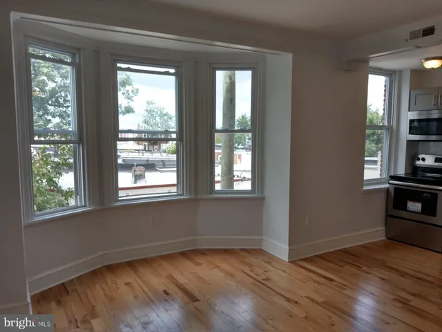 a view of an empty room with window and wooden floor
