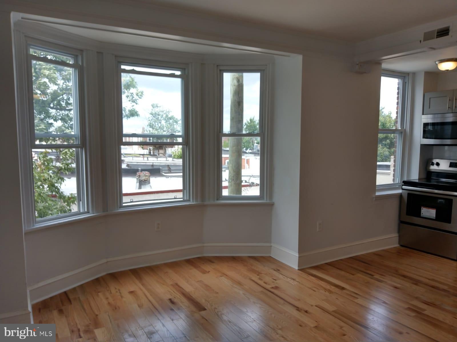 a view of an empty room with window and wooden floor
