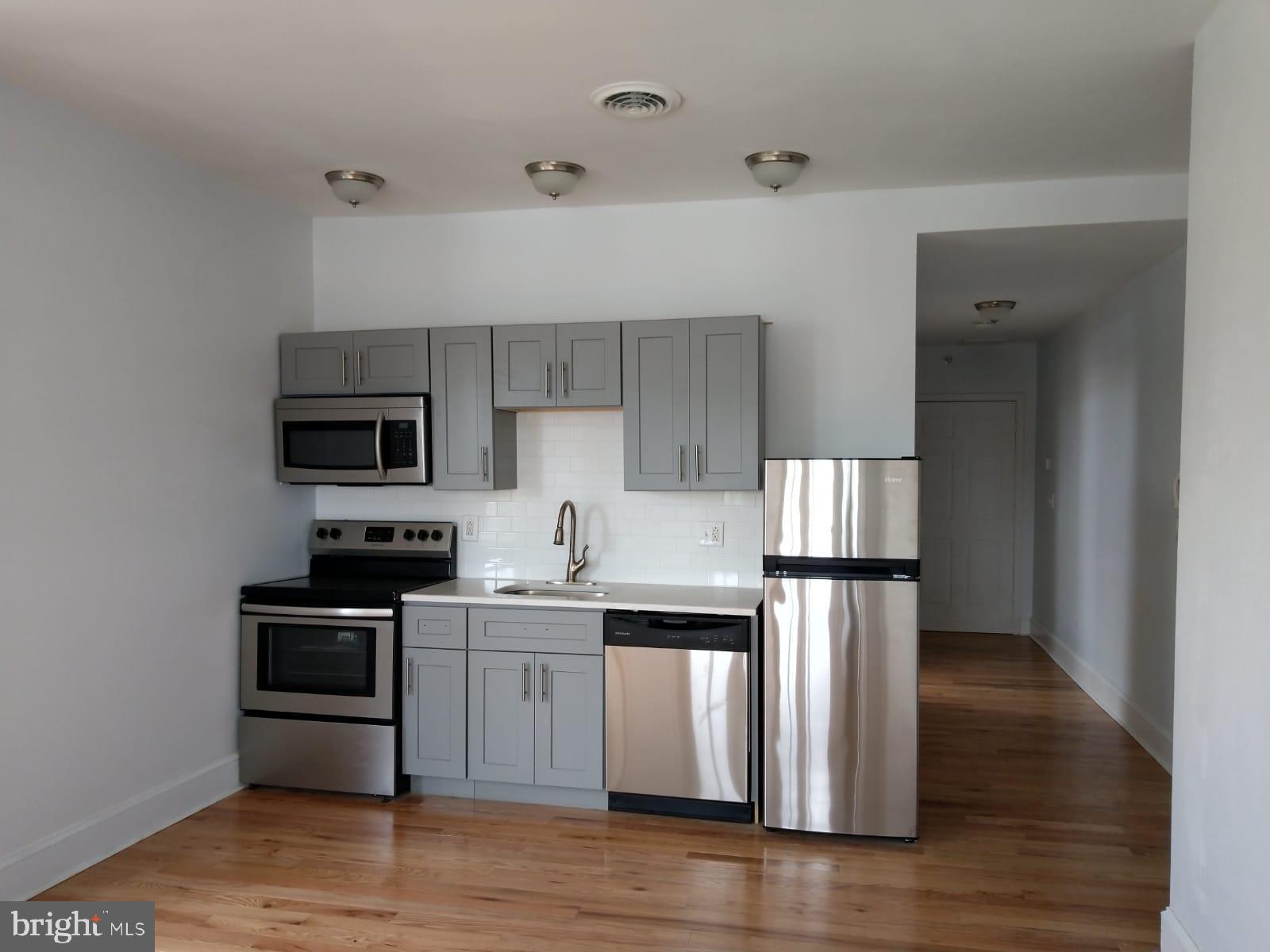 5913-17 Chestnut Street, Unit 4D Philadelphia, PA 19139 - Photo 2 of 4 a kitchen with stainless steel appliances a sink cabinets and wooden floor
