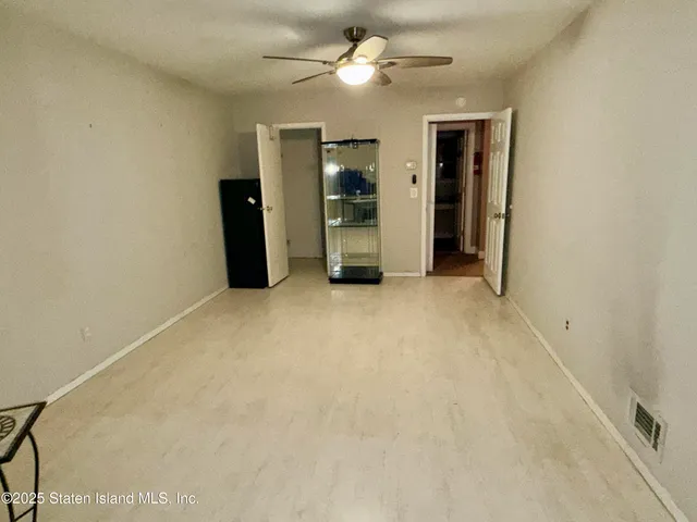 an empty room with closet and a ceiling fan