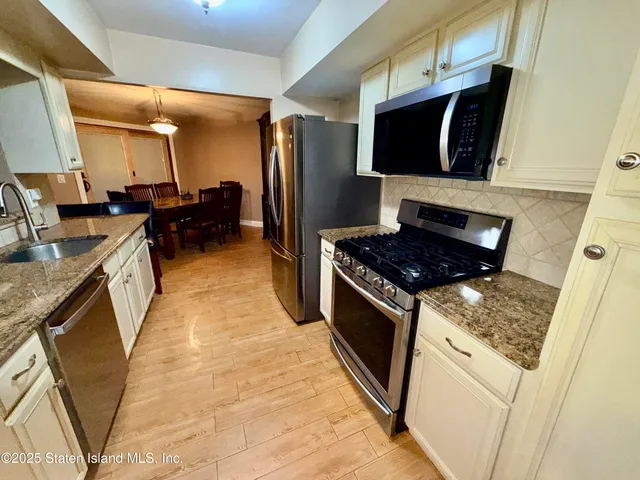 a kitchen with stainless steel appliances granite countertop a stove a sink and a microwave