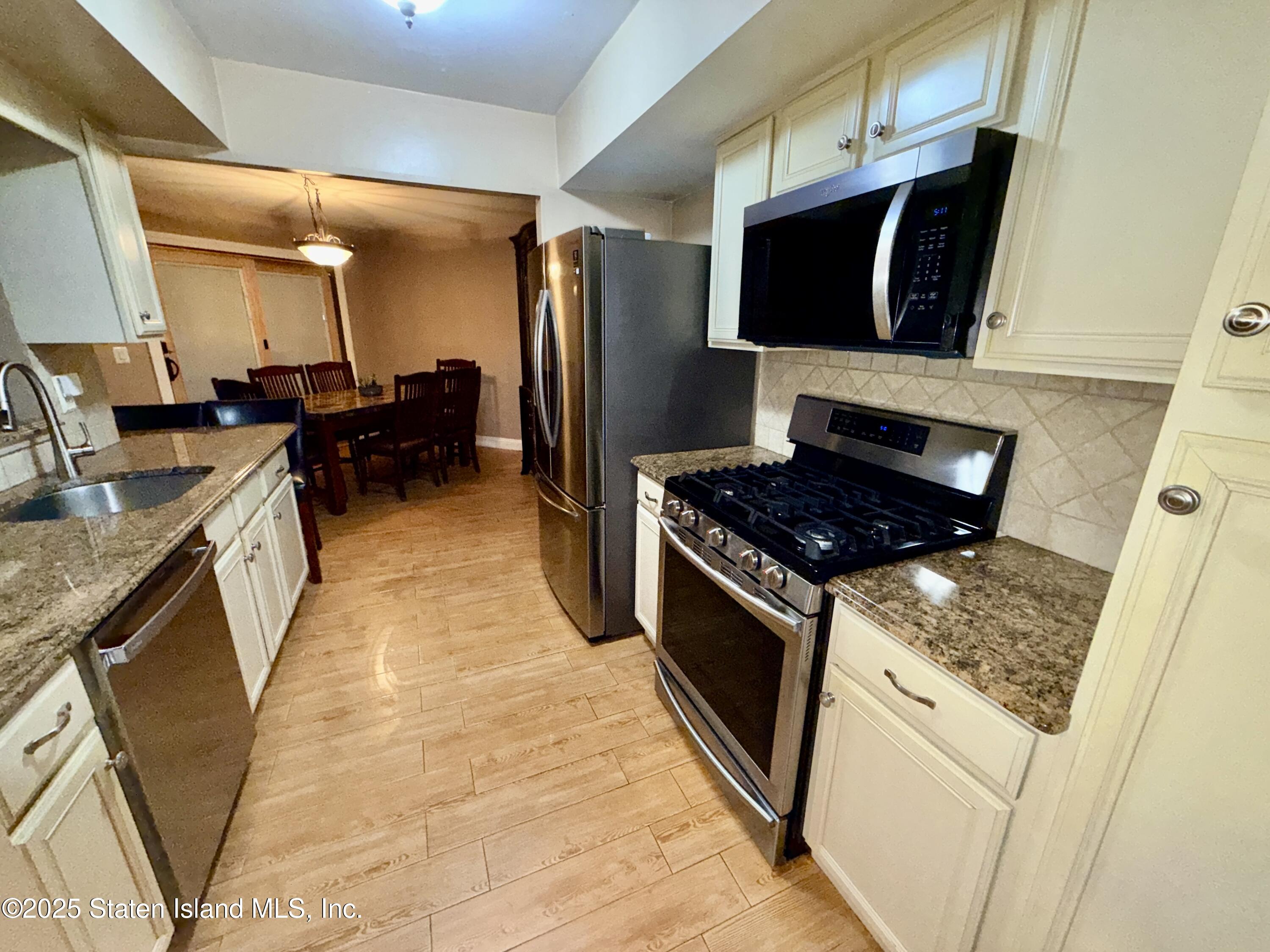 1446 Forest Hill Road, Unit 4 Staten Island, NY 10314 - Photo 6 of 24 a kitchen with stainless steel appliances granite countertop a stove a sink and a microwave